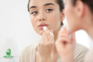 mengoleskan lip balm untuk menjaga kelembapan